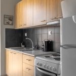 Sunny modern kitchen featuring wooden cabinets, appliances, and a balcony view.